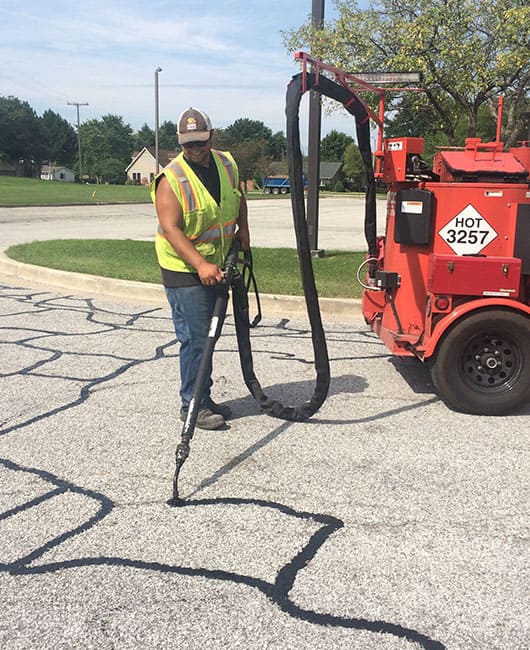 Site Services employee Crack sealing a parking lot