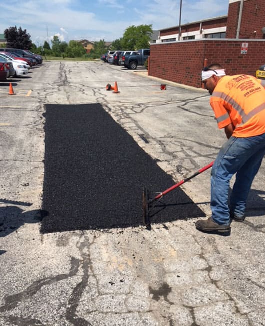 Site Services employee patching a parking lot