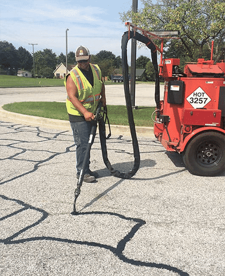 Site Services crew member with equipment crack sealing