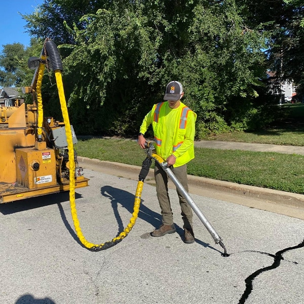 Site Services tech & equipment performing crack sealing in parking lot