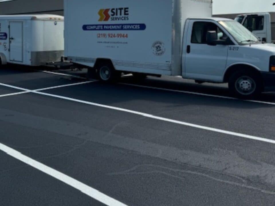 Site Services | A white "Site Services" truck parked on a newly paved and marked asphalt surface. The truck is attached to a white trailer.