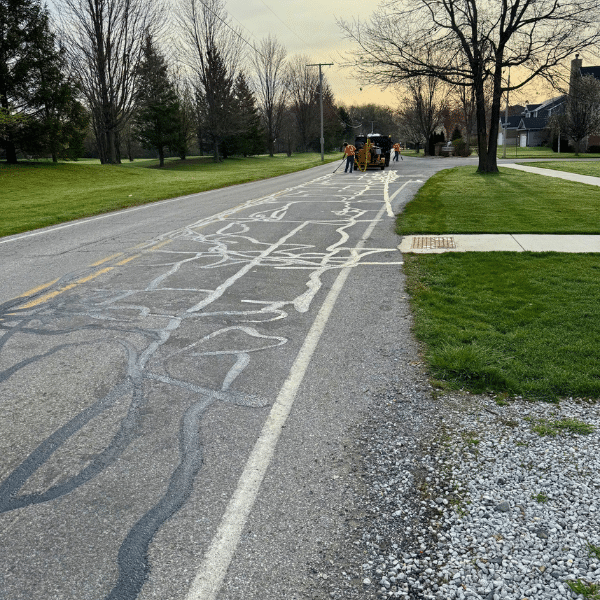 Site Services workers crack sealing a rural street with visible cracks.